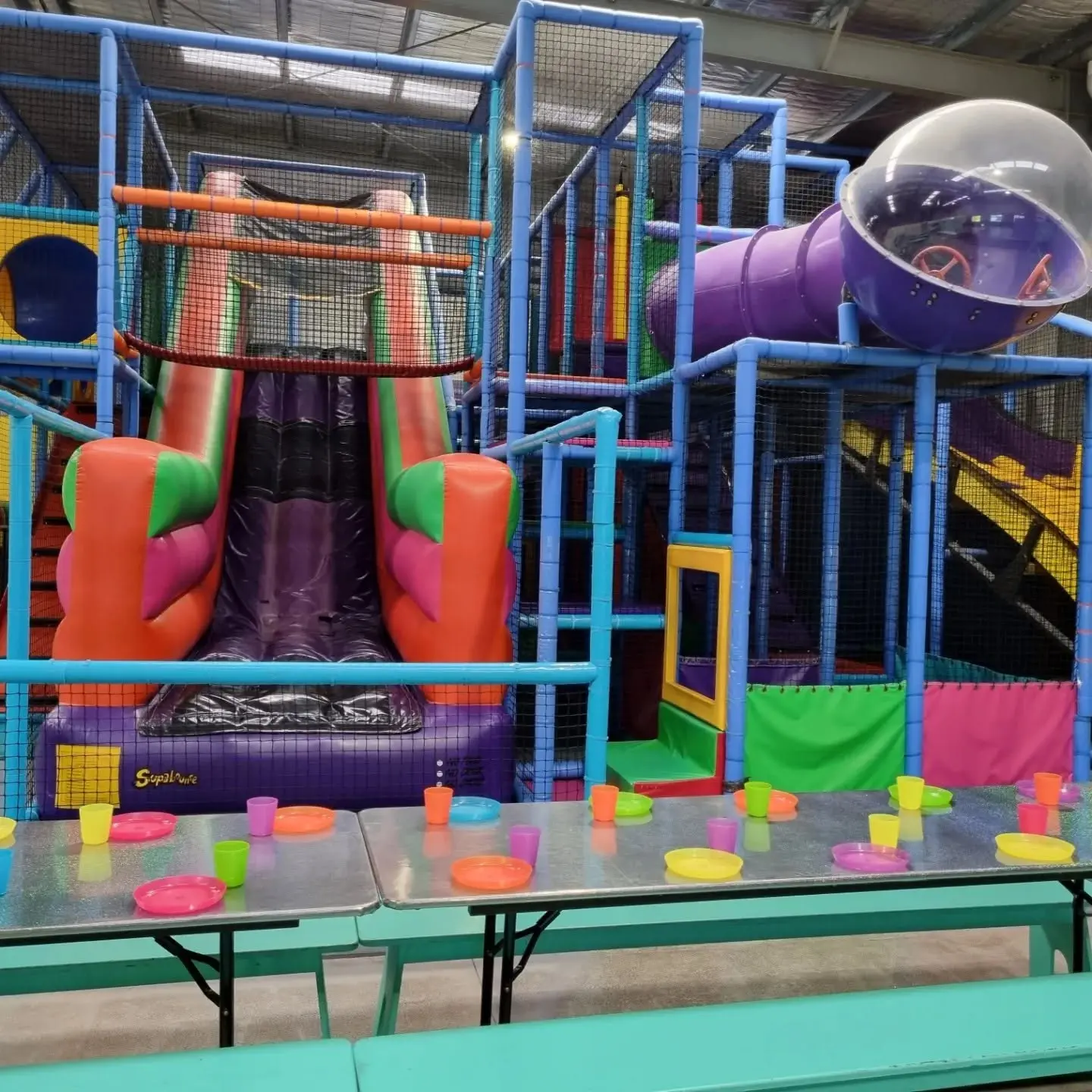 Multi-level indoor play structure with inflatable slide and party tables at Meerkat Manner, Ocean Grove
