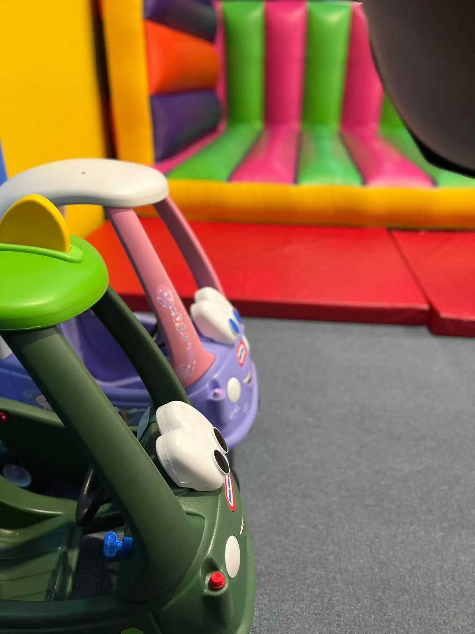 Ride-on toy cars next to an inflatable jumping castle at Meerkat Manner, Ocean Grove